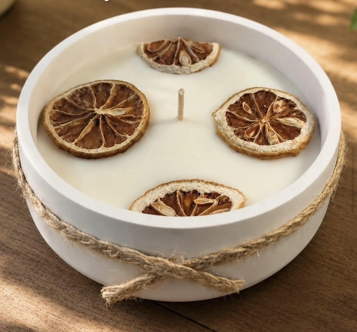 Bougie en coupelle blanche décorée de tranches d'agrumes séchées et entourée de ficelle de Fleurs de cire